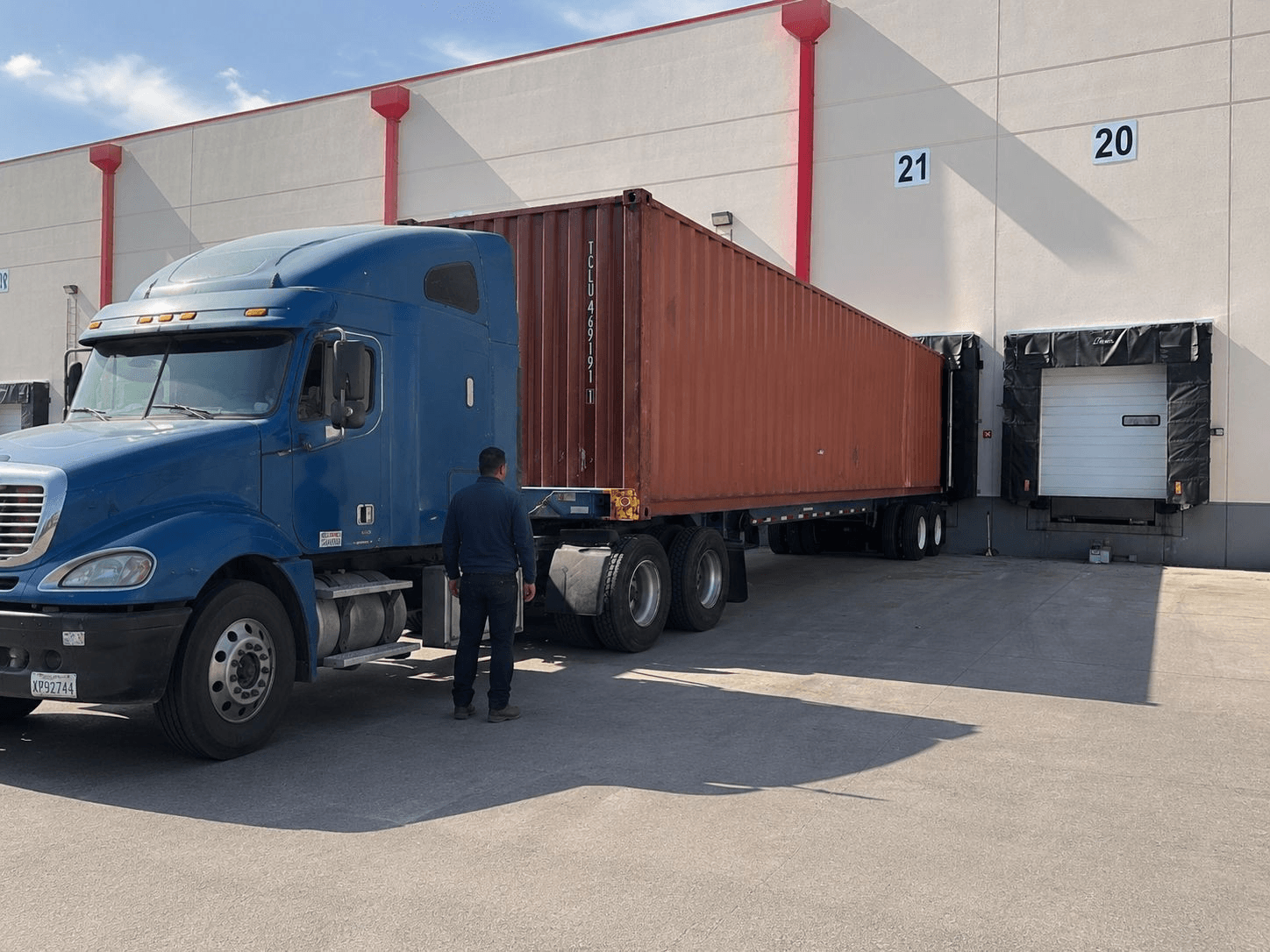 NBBL Group blue tractor delivering 40ft container at warehouse dock door 21 in Elizabeth, NJ